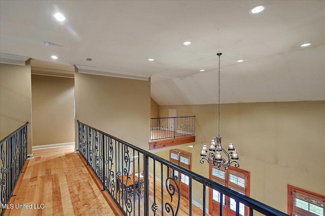 hall with crown molding, lofted ceiling, hardwood / wood-style floors, and a notable chandelier