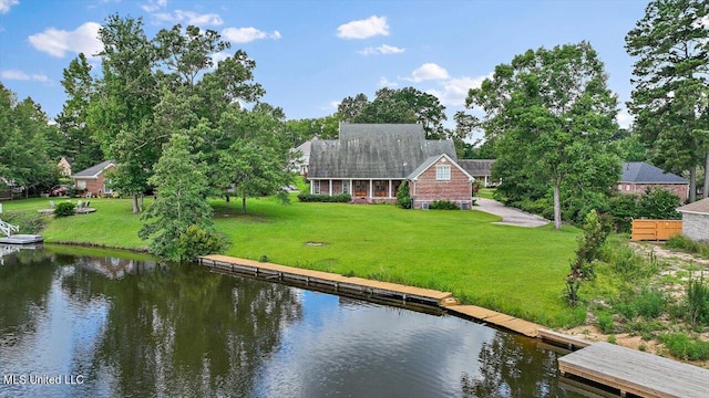 back of property with a water view and a yard