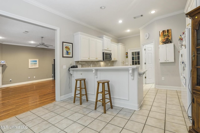 262 Geneva Blvd, Madison, MS 39110 - kitchen with stainless steel microwave, a ceiling fan, a peninsula, recessed lighting, and white cabinetry