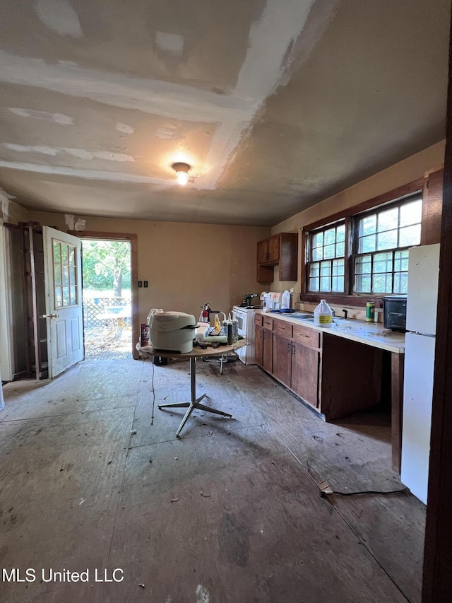 4595 Lucius Taylor Rd, Como, MS 38619 - kitchen featuring healthy amount of natural light, freestanding refrigerator, light countertops, and brown cabinets