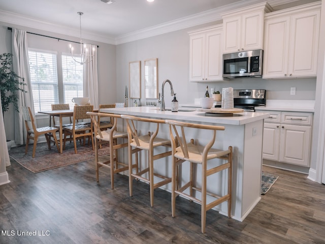 10501 Glade Cv, Gulfport, MS 39503 - kitchen featuring appliances with stainless steel finishes, a kitchen island with sink, a chandelier, dark wood finished floors, and light countertops