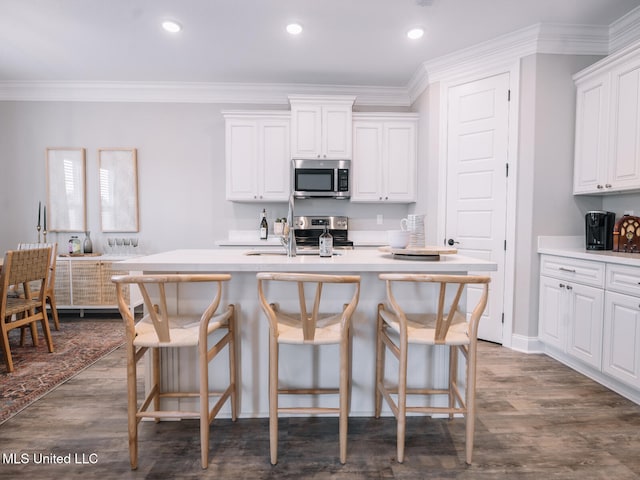 10501 Glade Cv, Gulfport, MS 39503 - kitchen with appliances with stainless steel finishes, a breakfast bar area, white cabinets, crown molding, and recessed lighting