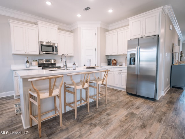 10501 Glade Cv, Gulfport, MS 39503 - kitchen featuring appliances with stainless steel finishes, white cabinetry, dark wood-style flooring, a center island with sink, and ornamental molding