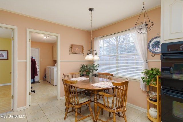 tiled dining room with ornamental molding and separate washer and dryer