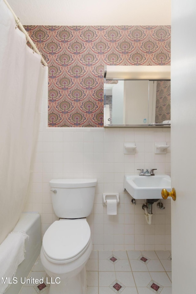 full bathroom featuring tile patterned floors, toilet, sink, and tile walls