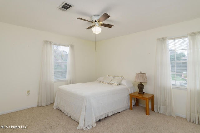 carpeted bedroom featuring multiple windows and ceiling fan