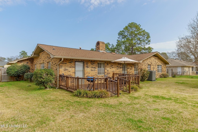 rear view of property featuring central AC unit, a lawn, and a deck