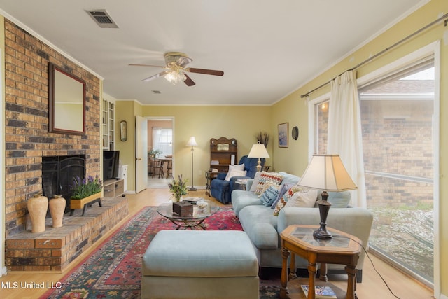 living room featuring ceiling fan, ornamental molding, and a brick fireplace