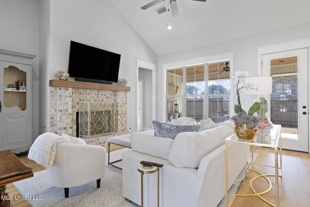 living area featuring visible vents, a ceiling fan, high vaulted ceiling, light wood-type flooring, and a tile fireplace