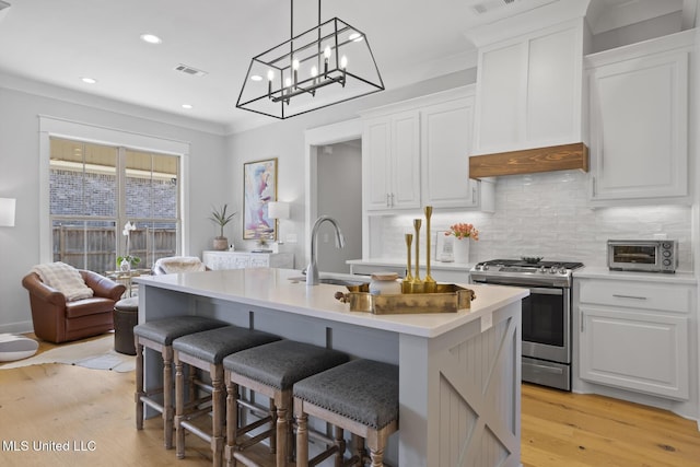 kitchen with light countertops, stainless steel gas range, and white cabinetry