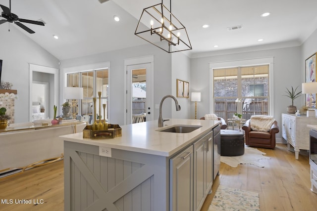 kitchen featuring a center island with sink, open floor plan, light countertops, gray cabinetry, and a sink