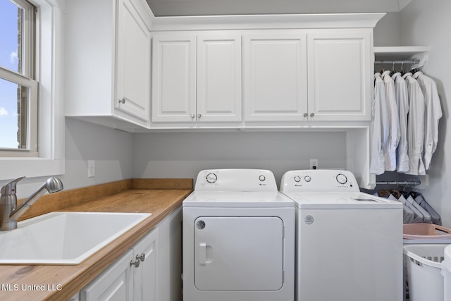 washroom featuring cabinet space, washing machine and dryer, and a sink