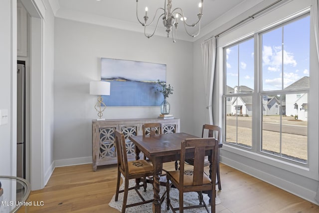 dining space with ornamental molding, light wood-style flooring, baseboards, and an inviting chandelier