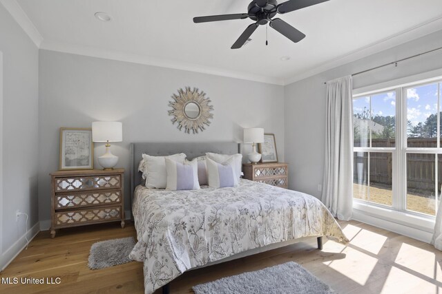 bedroom featuring a ceiling fan, crown molding, baseboards, and wood finished floors