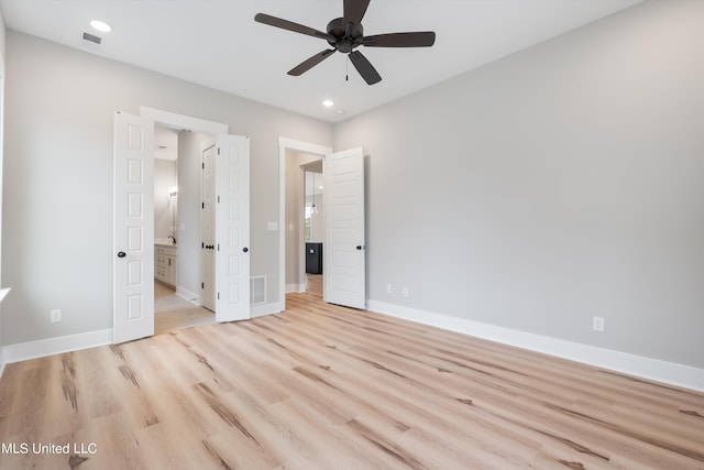 unfurnished bedroom featuring ceiling fan, light hardwood / wood-style floors, and connected bathroom