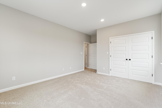 unfurnished bedroom with light colored carpet and a closet