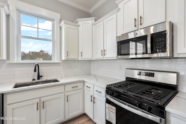 kitchen featuring backsplash, stainless steel appliances, white cabinetry, and sink