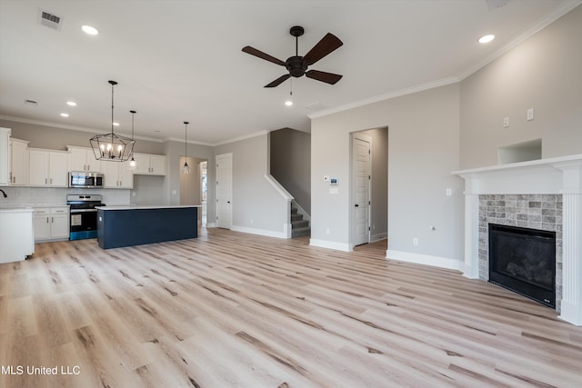 unfurnished living room with a tiled fireplace, ceiling fan, ornamental molding, and light wood-type flooring