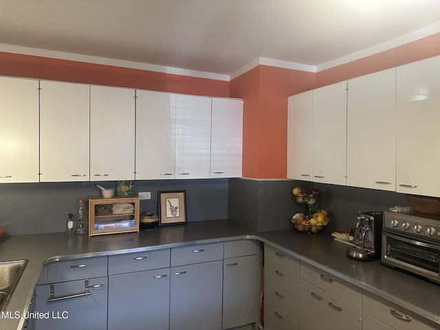 kitchen featuring white cabinetry, crown molding, and sink