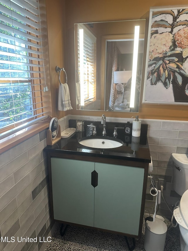 bathroom featuring vanity, tile walls, and toilet