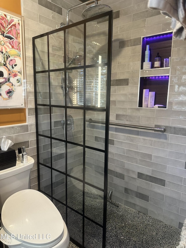 bathroom with a tile shower and toilet