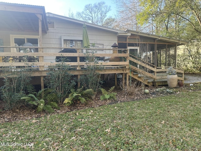 back of property with a sunroom, a deck, and a lawn