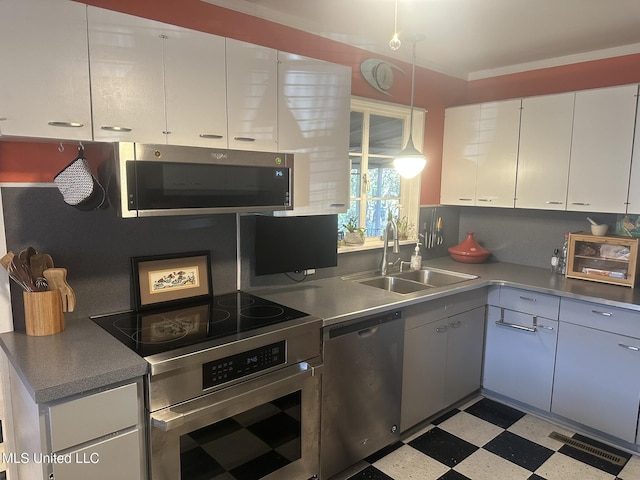 kitchen featuring pendant lighting, sink, white cabinetry, stainless steel appliances, and decorative backsplash