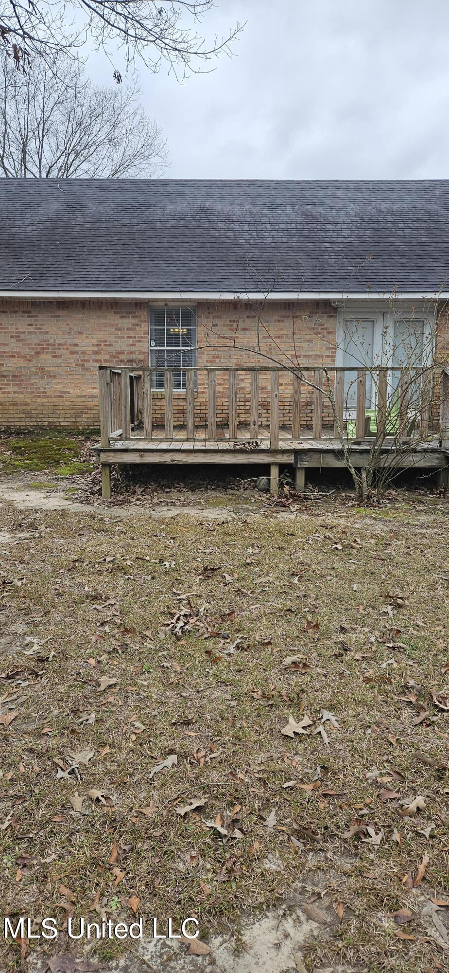 rear view of property featuring brick siding and a wooden deck