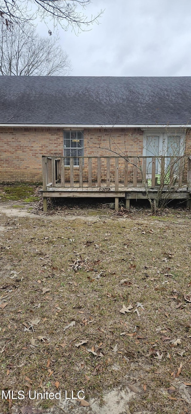 rear view of property featuring brick siding and a wooden deck