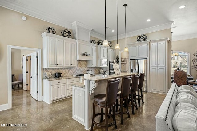 kitchen featuring stainless steel appliances, decorative backsplash, open floor plan, white cabinetry, and a kitchen breakfast bar