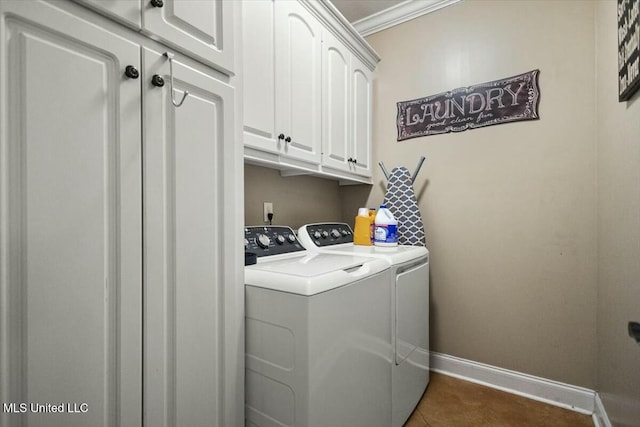 laundry area with cabinet space, baseboards, dark tile patterned flooring, crown molding, and washer and dryer