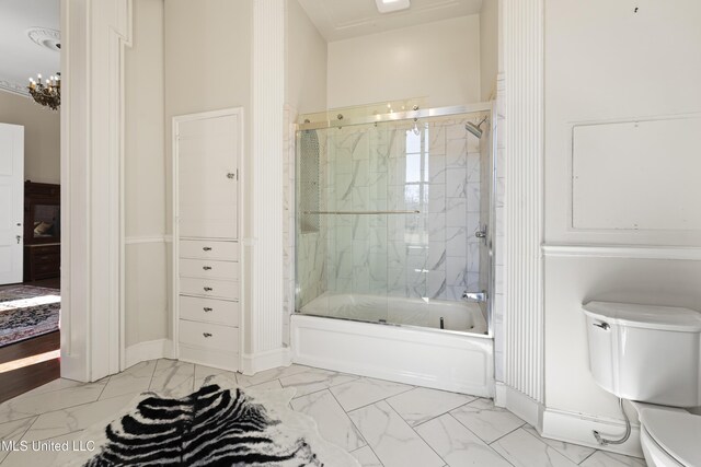 full bathroom featuring marble finish floor, baseboards, shower / bath combination with glass door, and toilet