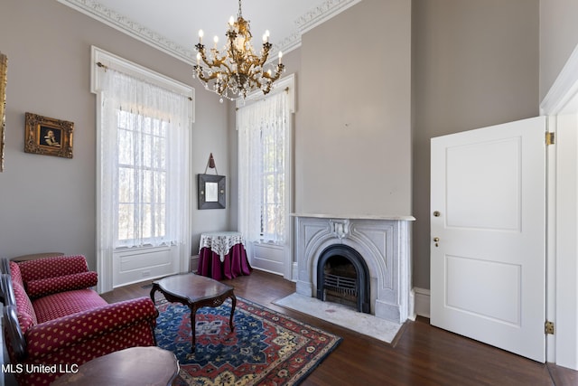 living area with a fireplace with flush hearth, ornamental molding, wood finished floors, and a chandelier