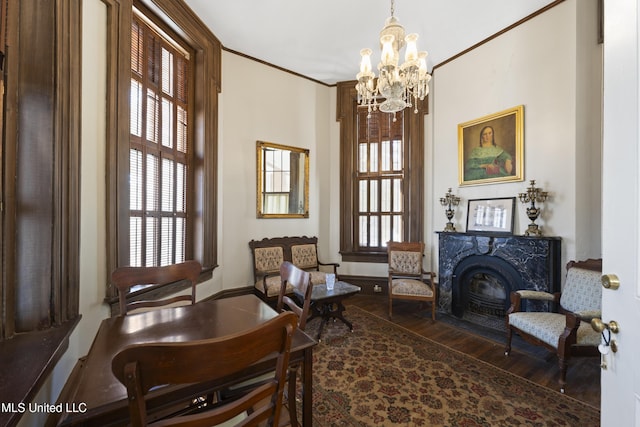 sitting room featuring a fireplace with flush hearth, a wealth of natural light, crown molding, and wood finished floors