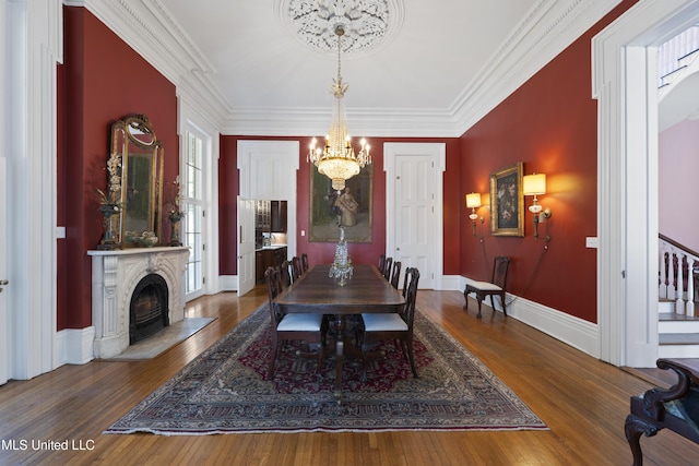 dining area featuring baseboards, ornamental molding, hardwood / wood-style floors, stairs, and a chandelier