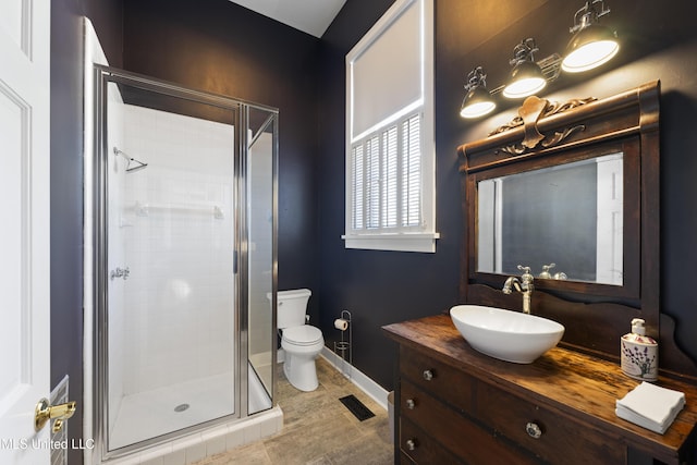 bathroom with visible vents, toilet, a shower stall, vanity, and baseboards