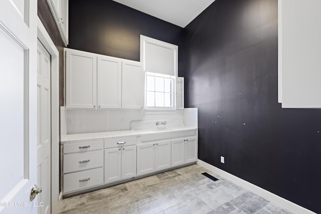 interior space featuring baseboards, visible vents, and a sink