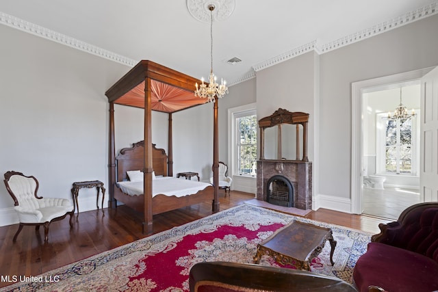 bedroom featuring wood finished floors, visible vents, a fireplace, and an inviting chandelier