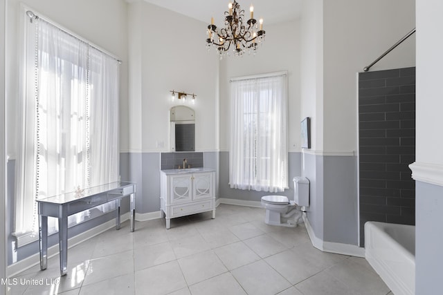 bathroom featuring a chandelier, toilet, vanity, baseboards, and tile patterned floors