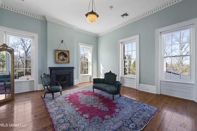 living area featuring wood-type flooring, visible vents, and baseboards