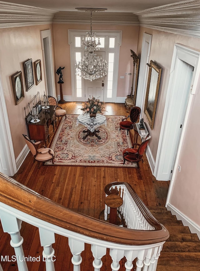 entrance foyer featuring baseboards, an inviting chandelier, hardwood / wood-style flooring, and crown molding