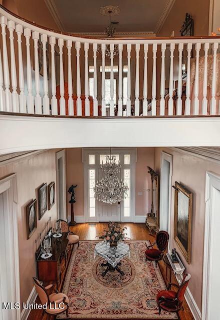 living room with a notable chandelier, baseboards, crown molding, and wood finished floors