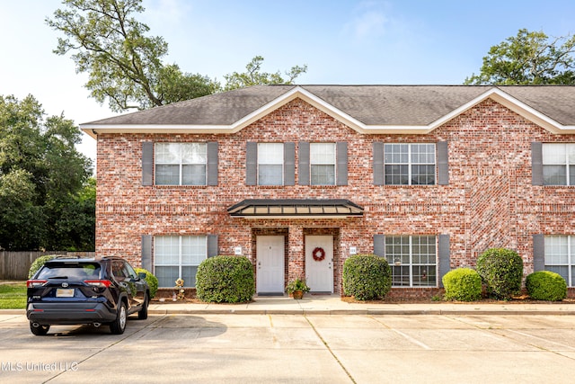 view of front of house featuring a shingled roof and brick siding