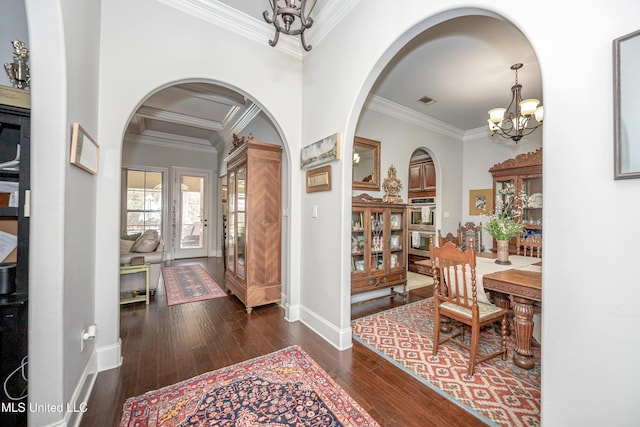 foyer featuring a chandelier, arched walkways, hardwood / wood-style floors, and crown molding