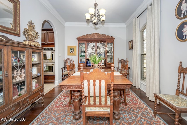 dining area featuring dark wood finished floors, crown molding, a notable chandelier, and arched walkways