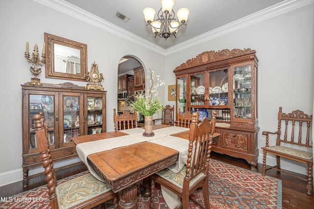 dining area featuring visible vents, a notable chandelier, wood finished floors, arched walkways, and crown molding