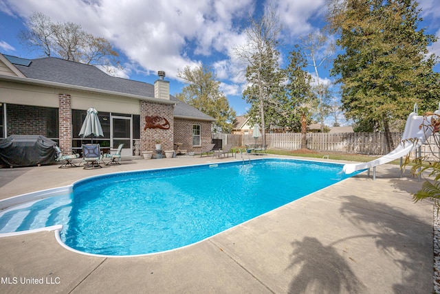 view of pool with a patio, a fenced in pool, a water slide, a fenced backyard, and grilling area