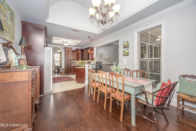 dining space featuring dark wood finished floors, visible vents, ceiling fan with notable chandelier, and ornamental molding