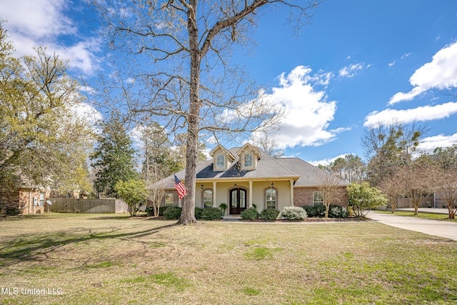 view of front of home featuring a front yard, fence, a shingled roof, french doors, and brick siding