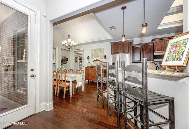 kitchen with dark wood-style floors, visible vents, ornamental molding, hanging light fixtures, and stainless steel fridge